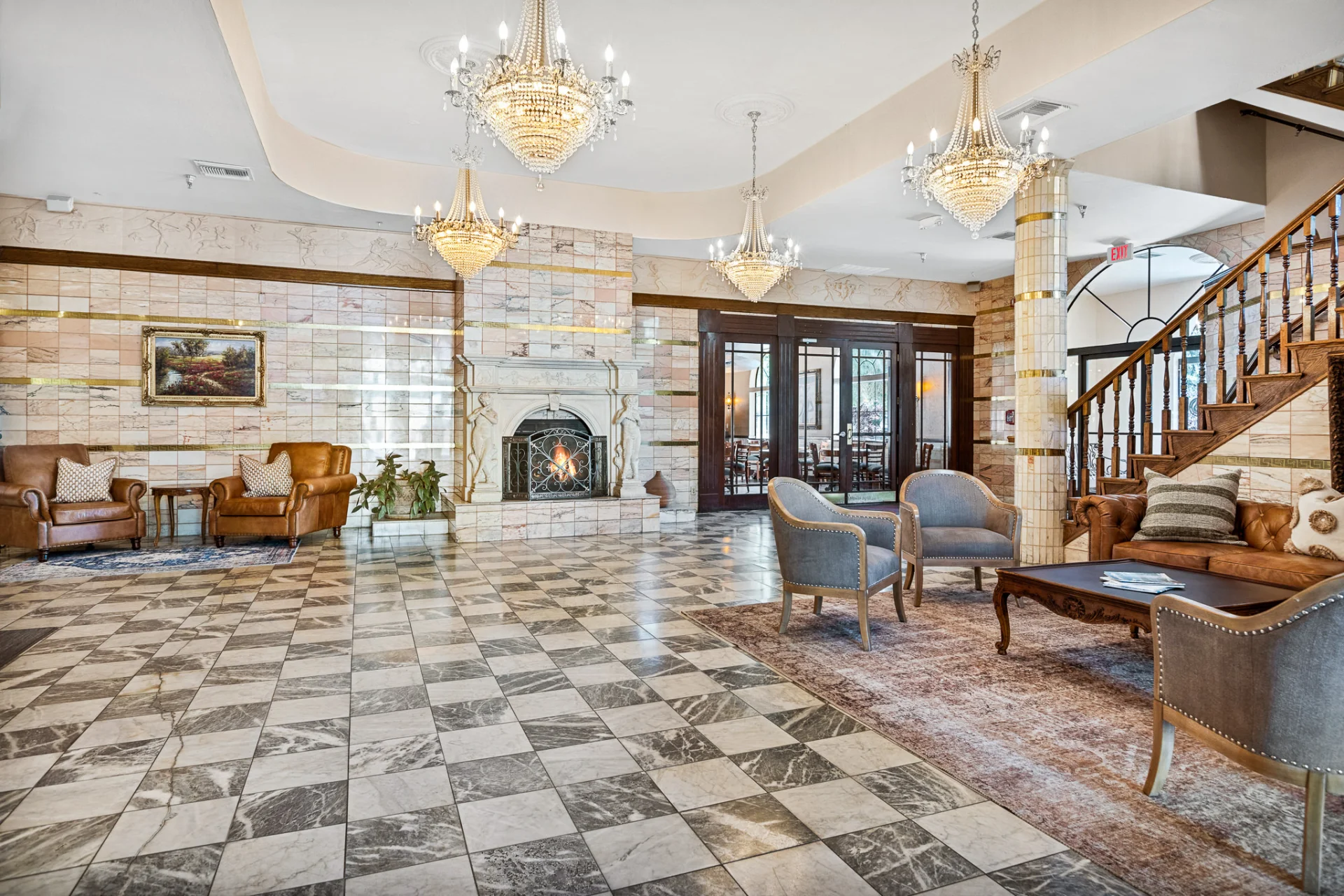 lobby checkered floor, chandeliers, fireplace, and grand staircase